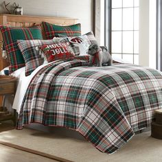 a plaid comforter set with a dog sitting on the pillow in front of it