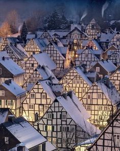 an aerial view of a city with lots of tall buildings and snow covered roofs at night