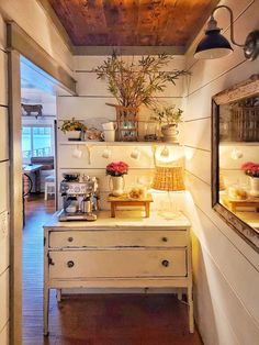 a kitchen with white walls and wooden ceilings, has plants on the shelf above the sink