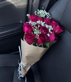 a bouquet of red roses sitting in the back seat of a car, with baby's breath