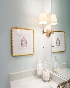 a bathroom sink with two framed pictures on the wall above it and a vanity mirror