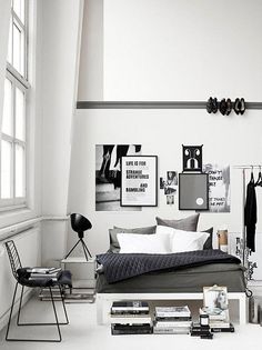 a bedroom with white walls, black and white furniture and pictures hanging on the wall