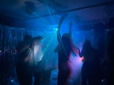 people dancing at a party with blue and green light coming from the ceiling behind them