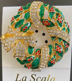 a brooch that is sitting on top of a white card with red and green beads