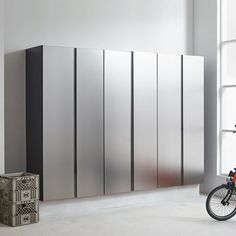 a bike parked next to a tall metal cabinet in front of a window with a bicycle leaning against it