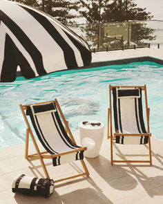 Poolside arrangement featuring black and white striped beach chairs and a matching umbrella. Perfect for lounging by the pool with stylish essentials like sunglasses and a side table. From Business & Pleasure Co. x Coco Republic collaboration.