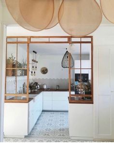 an open kitchen area with white cabinets and hanging lights above the counter top, along with potted plants