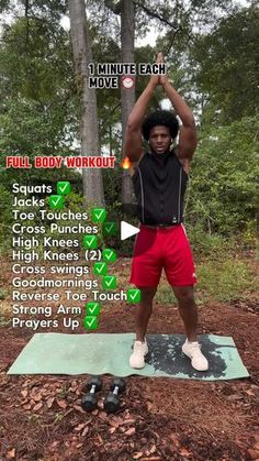 a man standing on top of a yoga mat in the woods with his hands up