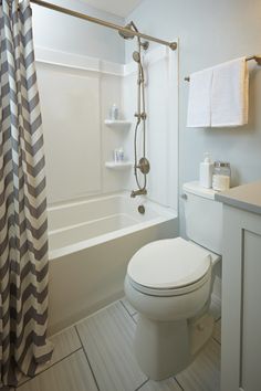 a white toilet sitting next to a bath tub in a bathroom under a shower curtain