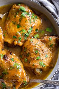 a bowl filled with chicken covered in gravy and garnished with parsley