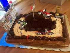 a motorcycle themed birthday cake with dirt bikes and flags on the top is ready to be eaten