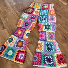 a multicolored crocheted afghan sits on the floor