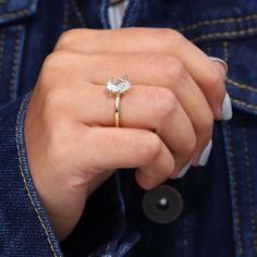 a close up of a person's hand wearing a ring with a diamond on it