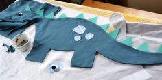 a stuffed dinosaur laying on top of a table next to a bowl and napkins