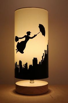 a lamp that is sitting on top of a wooden table with a silhouette of a person holding an umbrella