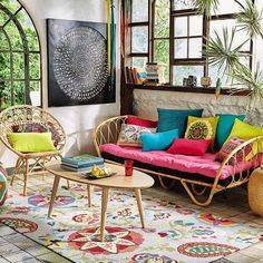 a living room filled with lots of furniture next to an open window and colorful rug