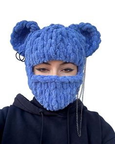 a woman wearing a blue knitted bear mask with chains on her face and ears