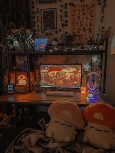 two stuffed animals are sitting in front of a computer monitor on a desk with other decorations