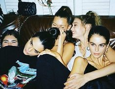 four women sitting on a couch with their arms around each other and one woman covering her face