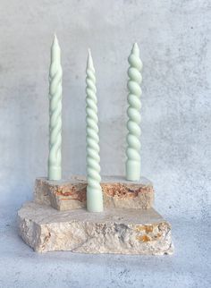 three candles sitting on top of a stone block