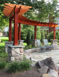 an outdoor patio with stone seating and pergolated arbors, surrounded by trees