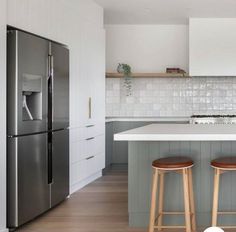 two stools are in front of the kitchen counter top and island with an icebox