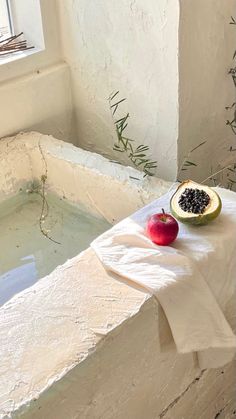 two pieces of fruit sitting on top of a towel next to a bathtub filled with water