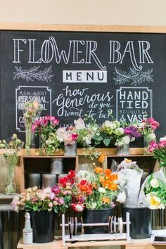 flowers are on display in front of a chalkboard with the words flower bar written on it