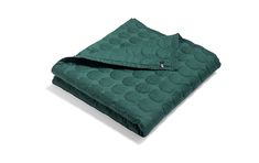 a green blanket folded on top of a gray surface with circles in the middle and bottom