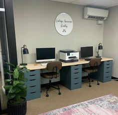 an office cubicle with two computers and a printer on the desk in front of it