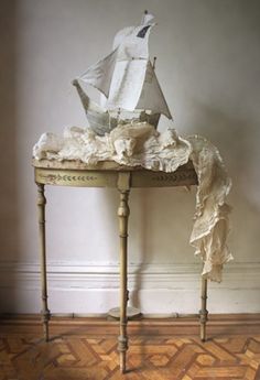 a small table with a sailboat on it and some fabric draped over the top