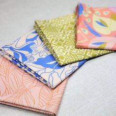 four different colored napkins sitting on top of a white cloth covered in fabric material