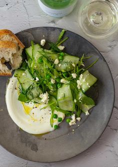 a plate with cucumber and bread on it next to a glass of water