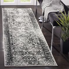 a black and white runner rug in front of a door with potted plants on the side