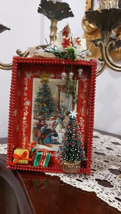 a red frame with a christmas scene on it and a small tree in the corner