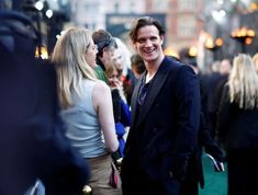 a man standing next to a woman on a green carpeted floor in front of a crowd