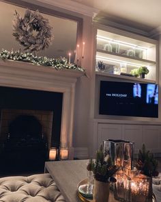 a living room with fireplace, couches and candles on the table in front of it