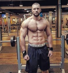 a shirtless man standing in front of a gym machine with his hands on his hips