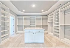 an empty walk in closet with white cabinets