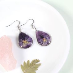 Handmade jewelry, pressed flower dangle earrings, pansy viola jewelry, real flower earrings, pressed flower earrings, violet earrings, February birth flower earrings, gift for her, birthday gift, purple flower jewelry, lightweight earrings, teardrop dangle earrings, silver, gold. Real pressed violet flowers are encased in resin in these lightweight teardrop dangles. Pansy viola flowers are grown, pressed, and individually selected for each earring. Each pair of earrings comes with silicone stopp Purple Pressed Flower Earrings, Purple Birth Flower Drop Earrings, Purple Pressed Flower Drop Earrings, Viola Flowers, February Birth Flower, Violet Jewelry, February Birth Flowers, Viola Flower, Violet Earrings