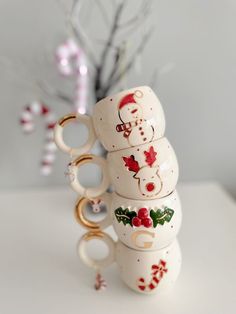 a stack of mugs sitting on top of each other in front of a christmas tree