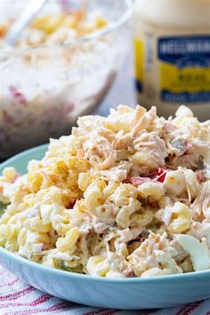 a blue bowl filled with chicken salad next to a container of mayonnaise