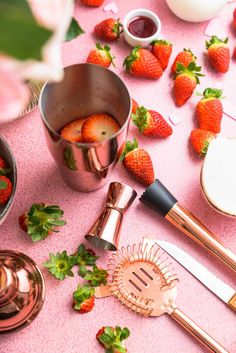 strawberries and other kitchen utensils on a pink table with rose gold accents