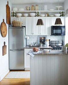 a white kitchen with stainless steel appliances and wooden flooring is pictured in this image