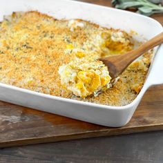 a casserole dish with cheese and bread crumbs in it on a wooden cutting board