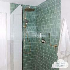 a green tiled bathroom with a shower head