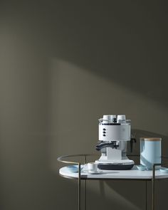 a coffee cup sitting on top of a glass table next to a grinder and other items