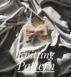 a bow tie laying on top of a white sheet with the words knitting pattern written below it