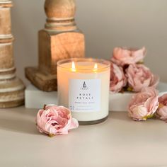 a candle with some pink flowers on a table