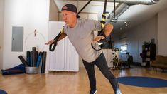 a man is doing aerial exercises in the gym while holding on to a pair of handles